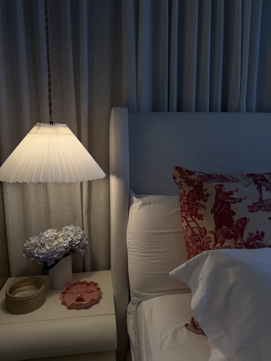 Moody bedside vignette with pleated lamp, toile pillow, and hydrangeas