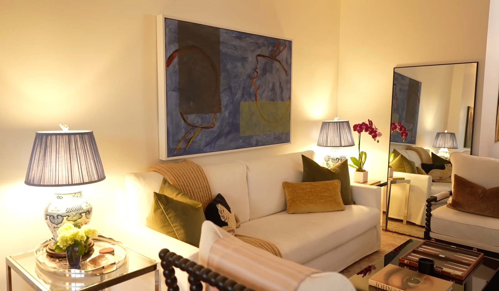 Elegant living room with blue abstract art, chinoiserie lamps, and warm evening lighting